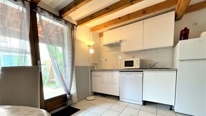 A compact kitchen with white cabinets, a microwave, a dishwasher, and a refrigerator. - Cozy Studio House with Mezzanine & Cabine - 6 Beds, 40m from Water, 3min to Beach, Parking Included (Gruissan)