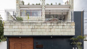 A modern building with a large wooden door, a balcony with metal railings, and a small tree in front. - Sleeps 9 Outdoor Space PingPong Table (Oaxaca)