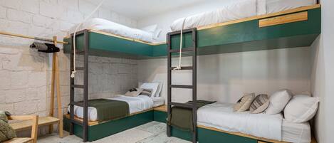 A bunk bed room with a wooden ladder, a small table with candles, and a chair.