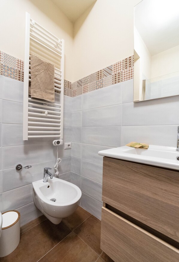 Une salle de bain équipée d’un bidet, d’un porte-serviettes, d’un lavabo et d’un miroir.