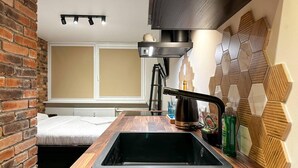 A compact kitchen with a black sink, wooden countertop, and a brick wall. - Beautiful 1-bed Apartment in Klaipeda (Klaipeda)