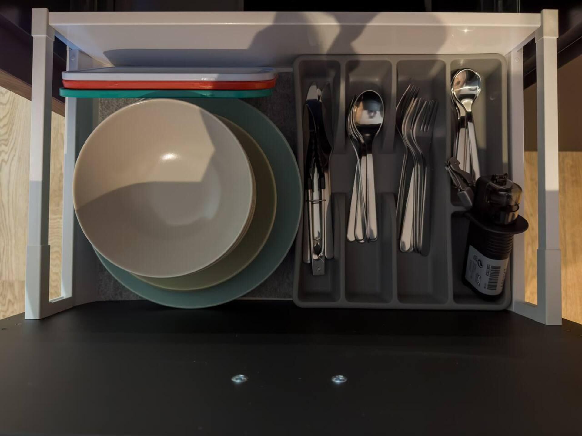 A drawer organizer with plates, bowls, and cutlery.