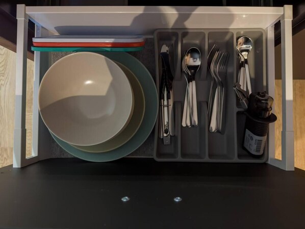 A drawer organizer with plates, bowls, and cutlery. - Beautiful 1-bed Apartment in Klaipeda (Klaipeda)