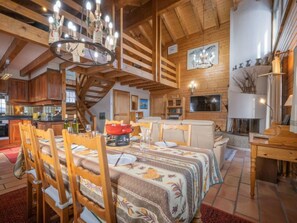 A spacious kitchen with wooden cabinets, a dining area with a table set for four, and a cozy living area with a fireplace. - Le Sorbier by Interhome (Ovronnaz)
