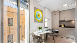 Een moderne keuken met een eethoek, grote ramen en uitzicht op het omliggende gebouw.