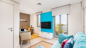 Una sala de estar moderna con un sofá azul, un escritorio blanco y un televisor de pantalla plana.
