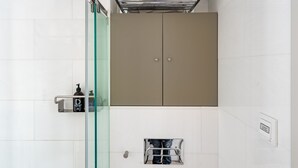 Un baño moderno con cabina de ducha de vidrio, un armario color beige y un perchero.