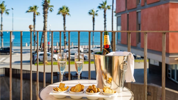 Ein Balkon mit Tisch, gedeckt für eine Mahlzeit, einer Champagnerflasche und zwei Sektgläsern.