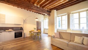 A modern kitchen with wooden beams, a dining area with chairs, a sofa, and large windows. - Dante´s Home Cozy in Center Town (Lucca)