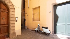 A narrow street with a white scooter parked by a building with a wooden door and a barred window. - Dante´s Home Cozy in Center Town (Lucca)