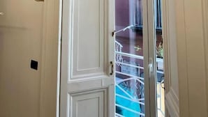 A white door with a glass panel, a brick wall, and a balcony with a railing. - Residenza Toledo (Naples)