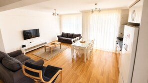 Een moderne woonkamer met een bank, een eettafel en een televisie.