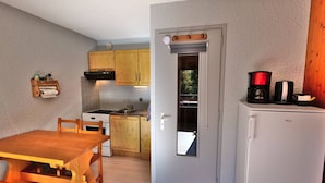 A compact kitchen with wooden cabinets, a stove, a sink, and a refrigerator.