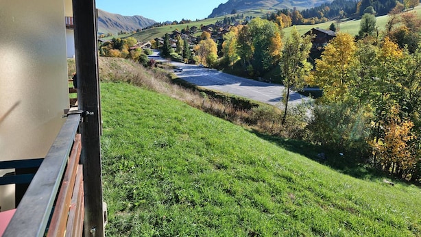 A view from inside a building overlooking a rural landscape with a road, houses, and mountains.