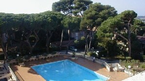 A swimming pool surrounded by trees and a building in the background.