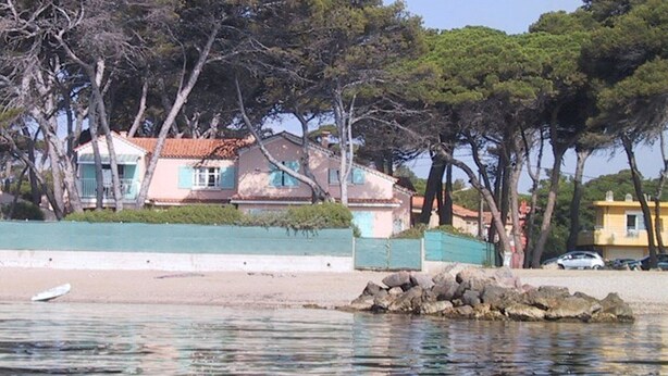 A coastal property with houses, a beach, and a rocky outcrop.