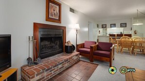 Una sala de estar con chimenea, televisor y comedor con muebles de madera.