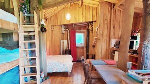 Una cabaña de madera con literas, un pequeño comedor y una kitchenette.