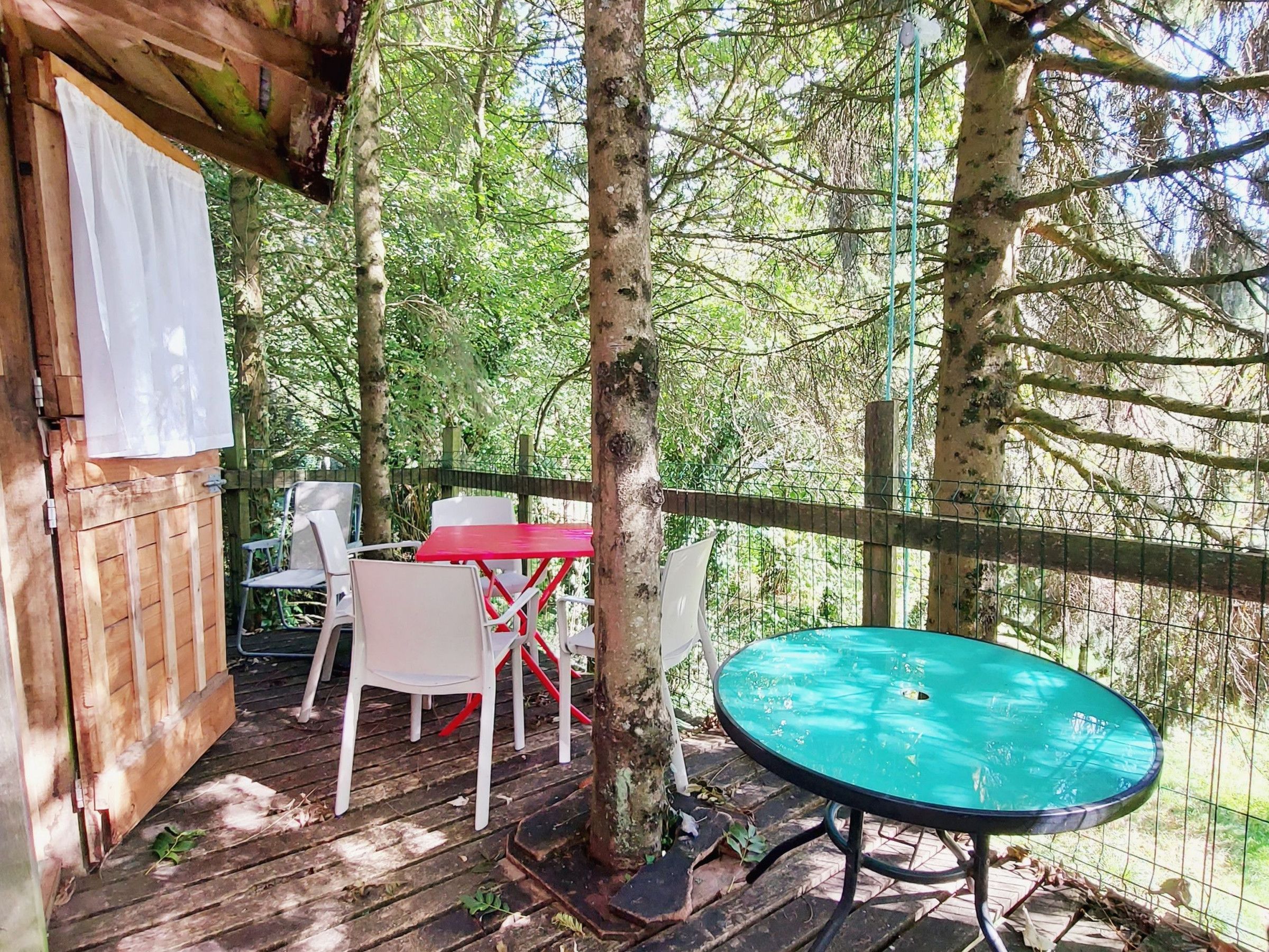 A wooden deck with a table and chairs, surrounded by trees.