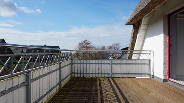 A balcony with a metal railing, a wooden deck, and a view of neighboring houses.