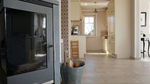 A modern kitchen with a built-in oven, a wooden ladder leaning against the wall, and a metal bucket filled with firewood.