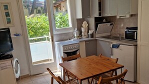 A compact kitchen with a dining table and chairs, a stove, a microwave, and a refrigerator.