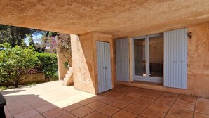 A covered patio area with tiled flooring, a stone wall, and a door with a window.
