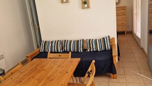 A dining area with a wooden table and chairs, a dark-colored sofa with striped cushions, and two wall-mounted planters.