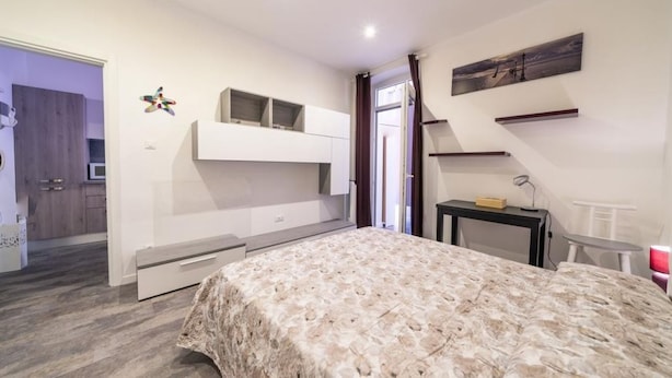 Quarto com cama, armários embutidos, escrivaninha e vista para o exterior.