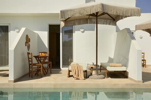 Un área de piscina moderna al aire libre con una tumbona, una mesa y un conjunto de comedor.
