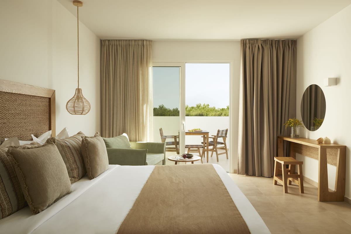 Una habitación de hotel moderna con una cama grande, un escritorio y un balcón con cortinas.