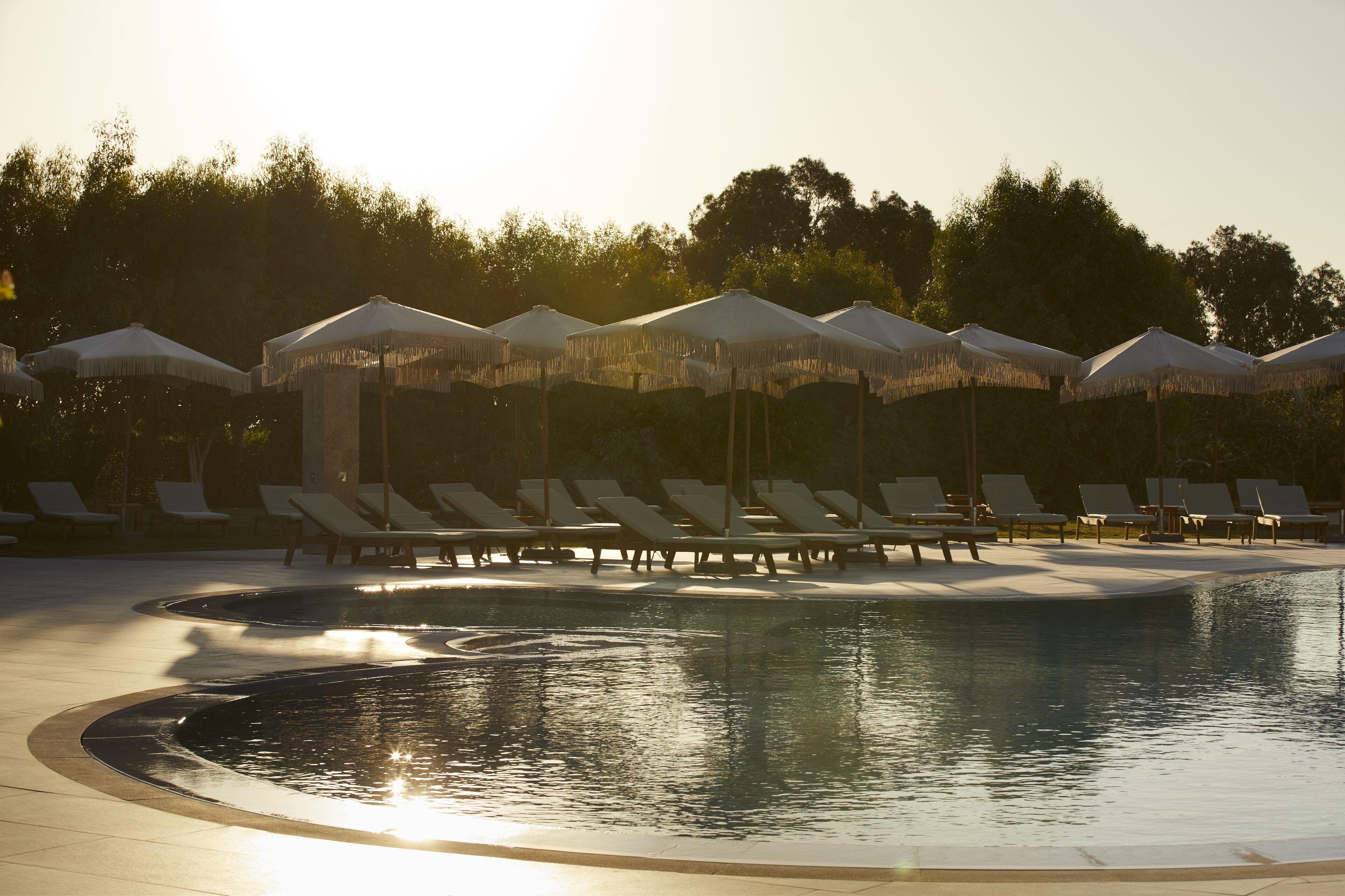 Un espace piscine équipé de chaises longues et de parasols.