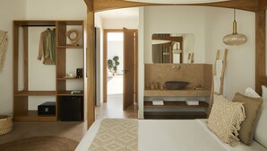 Un dormitorio moderno con una cama grande, un armario de madera, un escritorio empotrado y un baño con un espejo grande y lavamanos.