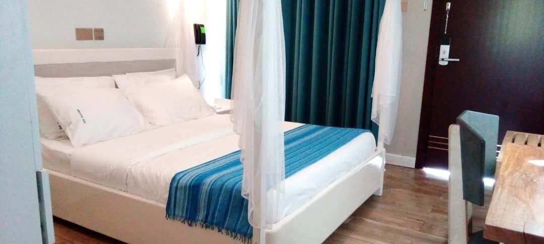 A bed with white bedding, a blue-striped throw, and a canopy.