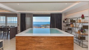 Une chambre moderne dotée d’une grande piscine intérieure à parois de verre, d’un coin repas et offrant une vue sur la mer.