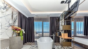 Une salle de bain moderne avec une baignoire sur pieds, un sol en marbre et une grande fenêtre donnant sur la mer.