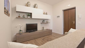 A modern bedroom with a bed, a TV on a wooden console, and decorative items on shelves. - Esseneto Rooms (Agrigento)