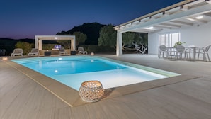 Una piscina con sillones de descanso y una pérgola.