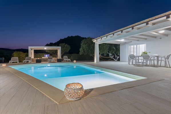 A swimming pool with lounge chairs and a pergola.