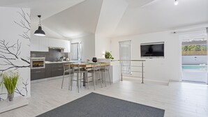 Una cocina moderna con comedor, televisor y vistas a la piscina.
