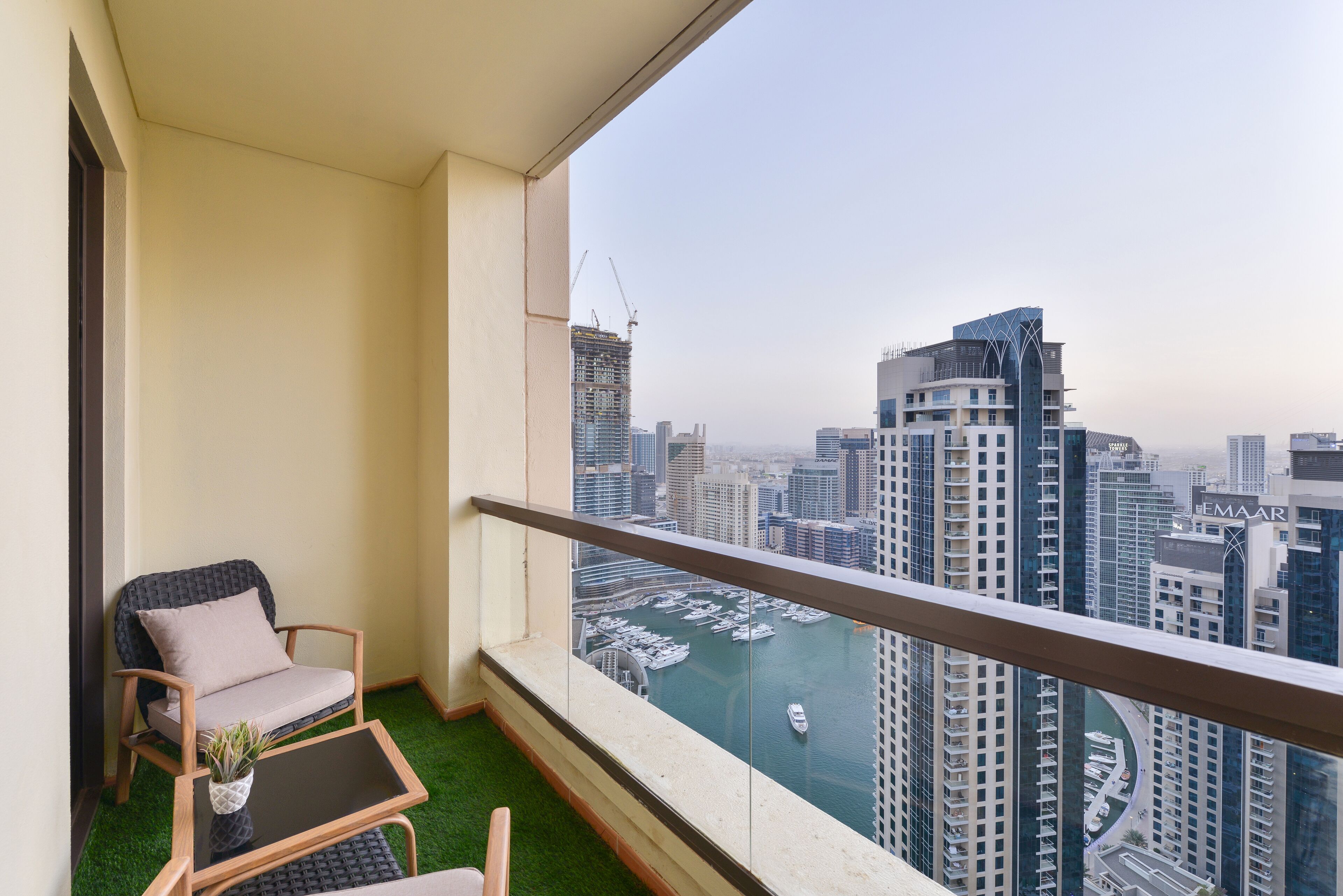 A balcony with a view of a marina and high-rise buildings.