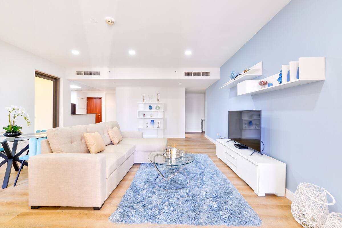 A modern living room with a sofa, glass coffee table, and TV.