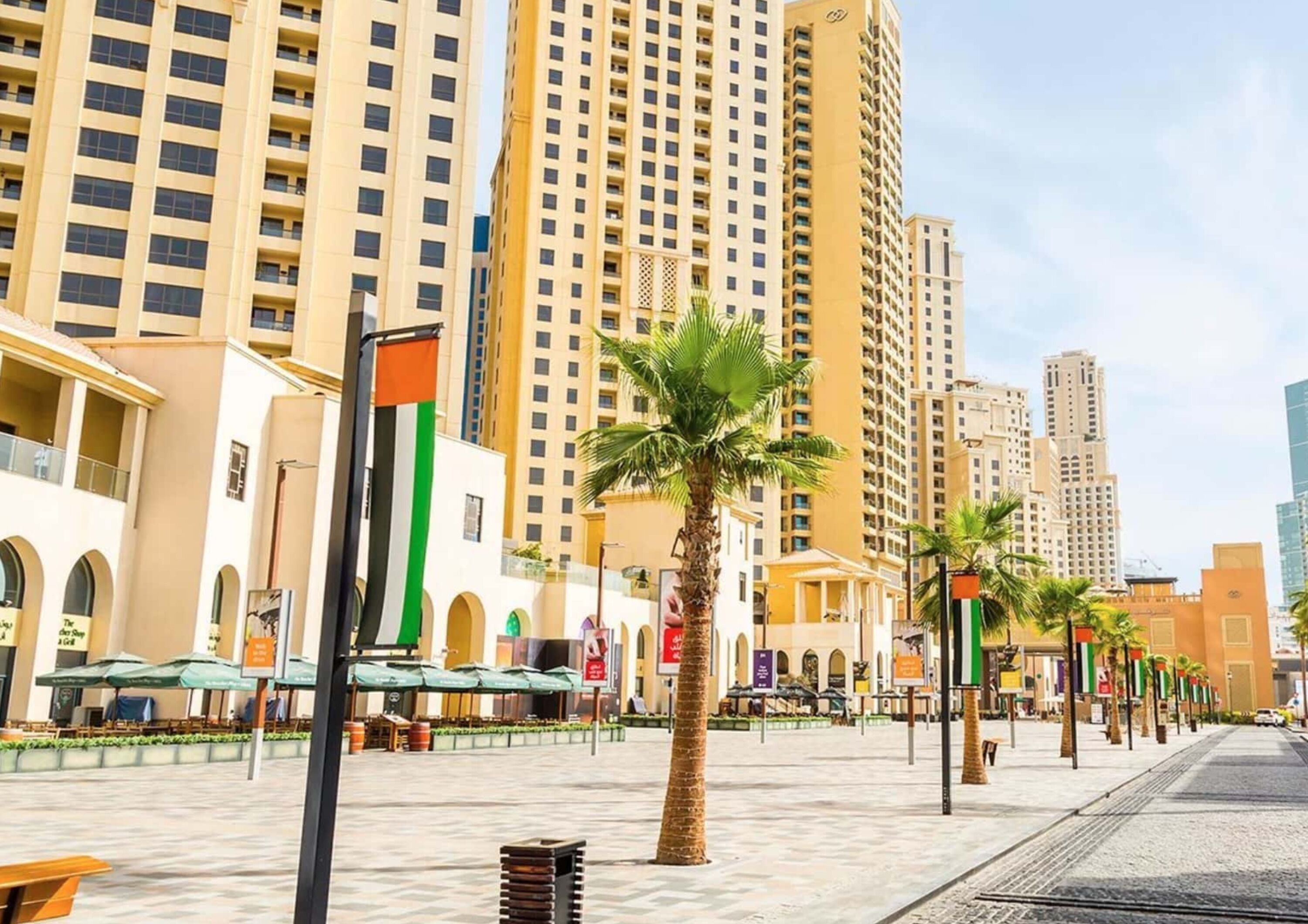 Una plaza urbana moderna con rascacielos, palmeras y zonas de estar al aire libre.