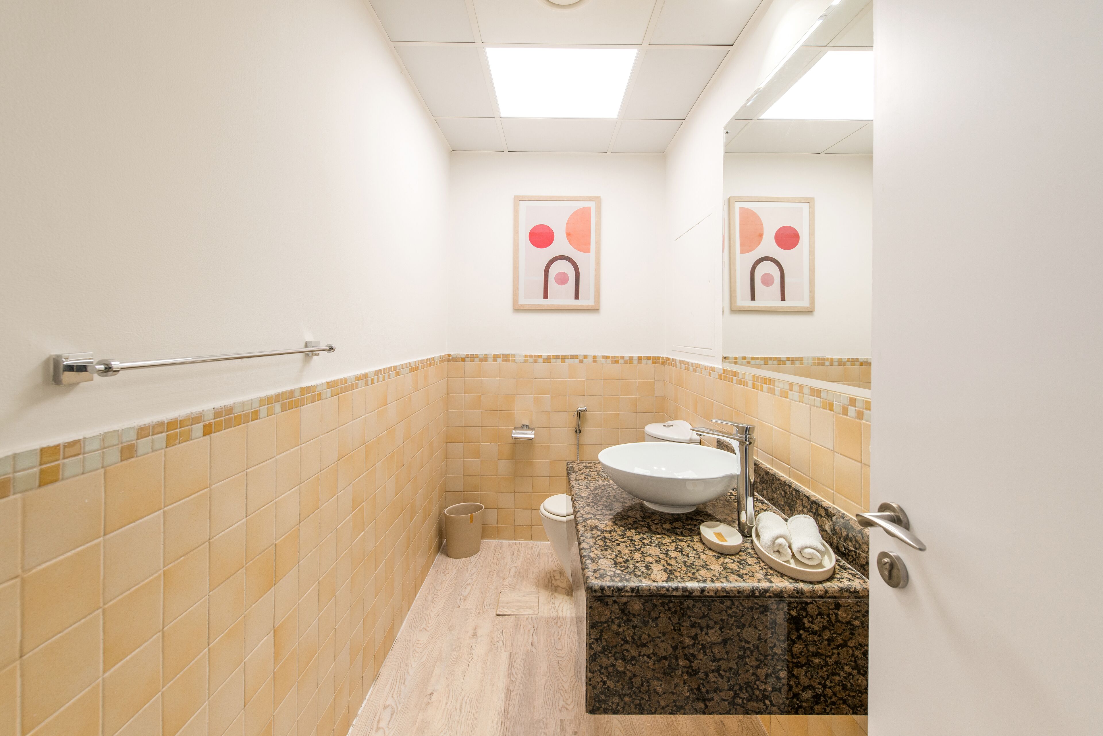 Et badeværelse med toilet, vask og håndklædestige.