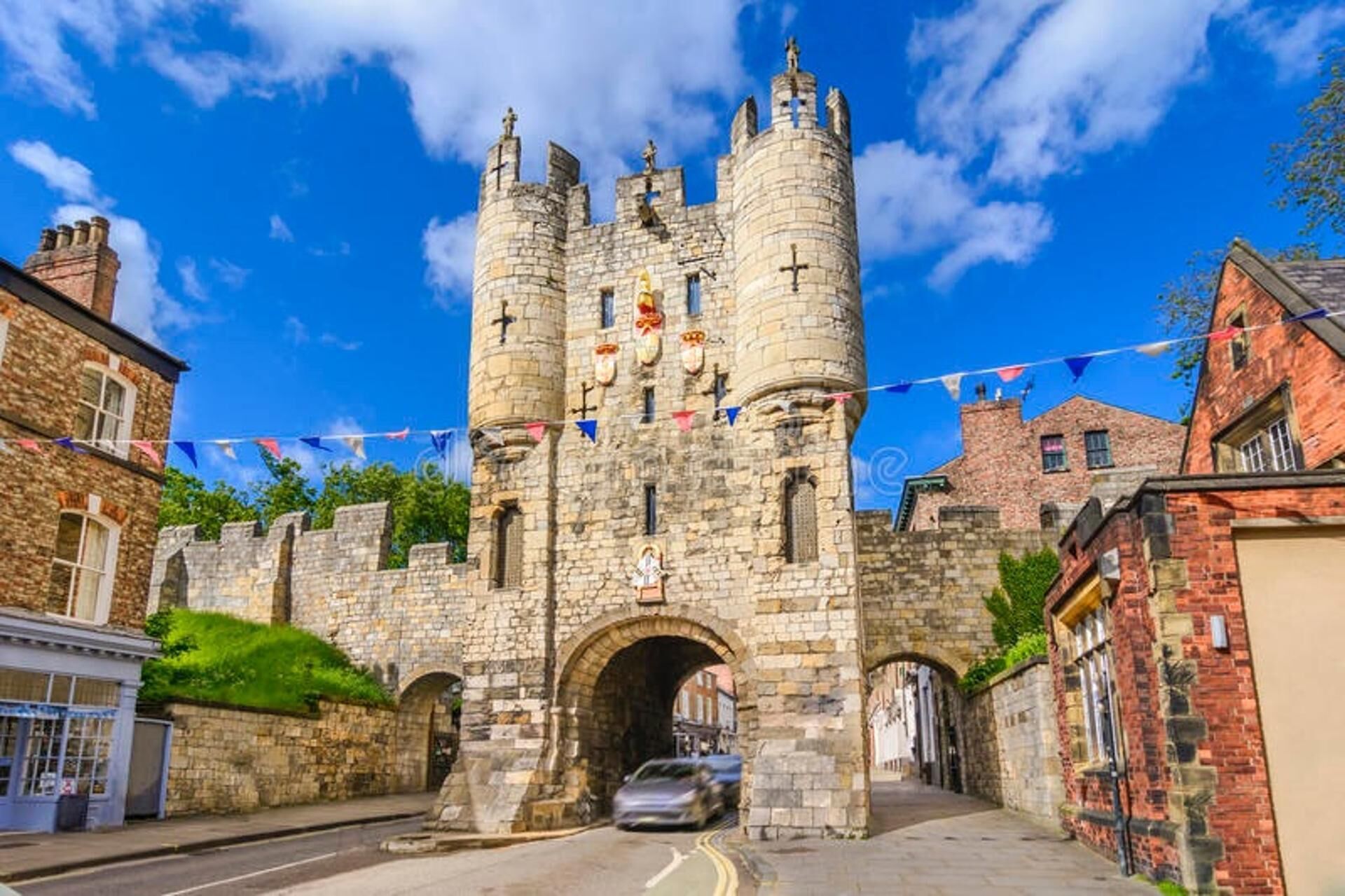 Un castillo de piedra histórico con dos torres, un arco central y una calle al frente.