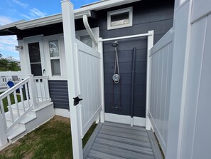 A two-story house with a dark grey exterior and white trim. There is a front door with a small window above it, and a set of stairs leading to the front porch.