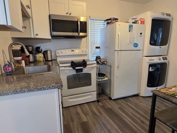 A compact kitchen with white appliances, including a microwave, oven, and refrigerator.