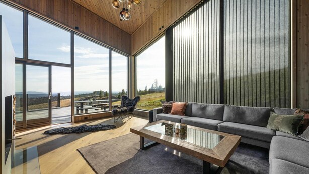 A modern living room with large windows, a grey sofa, a coffee table, and a view of a mountainous landscape. - Stunning view in holiday home (Gol)
