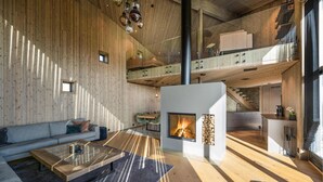A spacious living area with a fireplace, wooden walls, and a modern kitchen. - Stunning view in holiday home (Gol)