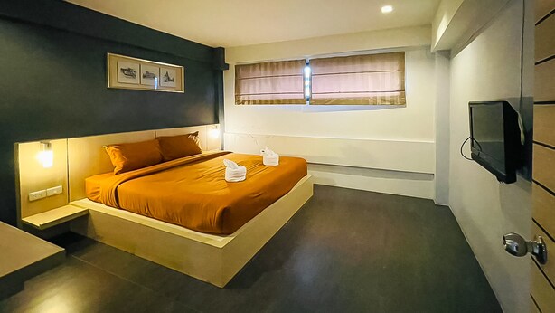 Quarto moderno com cama, abajures, televisão e janela com cortinas.